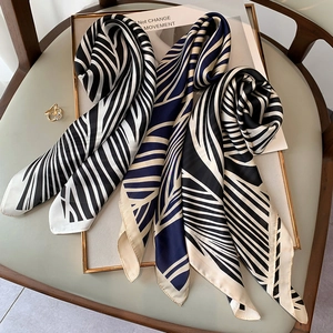 Detail of silk scarves with zebra and leaf patterns on a display board with a ring