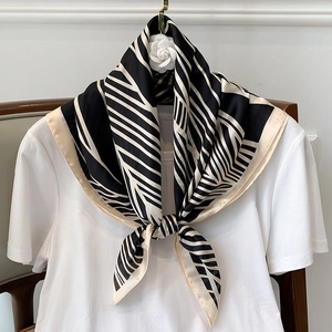 Detail of a silk scarf tied on a white tee shirt featuring black and white geometric stripes