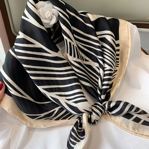 Detail of a silk striped scarf with camellia flower knot on a white blouse