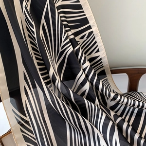 Detailed view of a black and white striped silk scarf draped on a chair for elegant texture