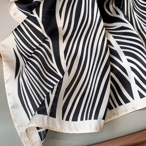 Close-up of black and white striped silk scarf with abstract leaf vein texture on soft seat