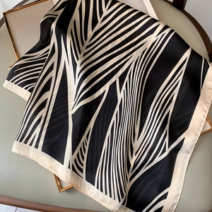 Detail of elegant black and white geometric silk scarf draped on a gold frame