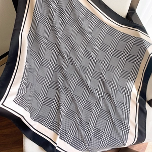 Detailed view of large houndstooth pattern scarf with black and beige borders on a chair