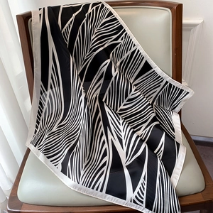 Close-up of black and white leaf pattern silk scarf draped on a leather chair