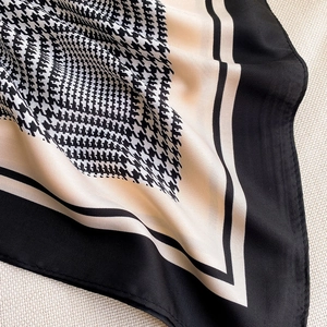 Macro shot of houndstooth silk scarf showing fine twill texture and black border detail