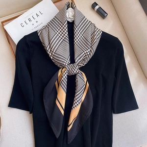 Classic houndstooth silk scarf with gold accents styled over a black knit sweater