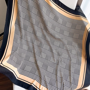 Close-up of silk houndstooth scarf showing premium texture and khaki border detail
