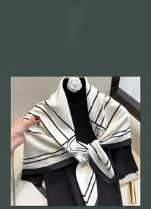 Dettaglio di un foulard quadrato effetto seta con stampe geometriche e spilla a fiore