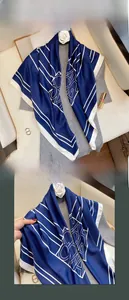 Dettaglio di un foulard quadrato blu scuro in finta seta con motivi geometrici bianchi