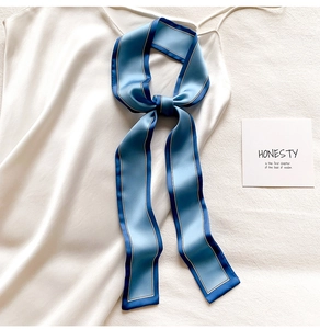 Gros plan d'un élégant foulard twilly en soie à rayures bleues noué sur un haut blanc