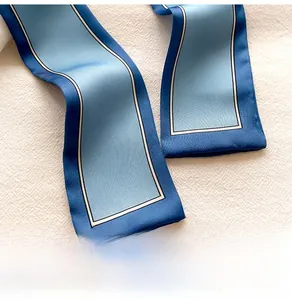 Macro d'un foulard twilly en satin bleu avec élégant liseré noir et blanc sur tissu