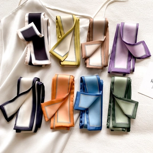 Détail de foulards étroits en satin aux couleurs variées avec bordures contrastées