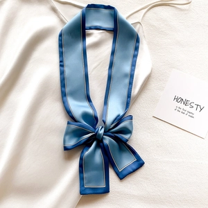 Détail d'un foulard twilly bleu en patchwork noué sur une robe en satin blanc