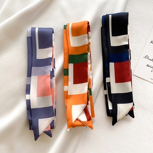 Détail de trois foulards twilly géométriques en satin de soie lavande, orange et marine