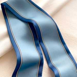 Détail d'un foulard en soie à rayures bleues montrant la texture sergée et les finitions