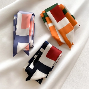 Trois longs foulards en soie aux motifs géométriques sur fond de satin blanc