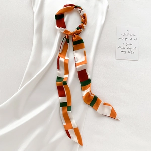 Élégant foulard en soie à motif géométrique avec anneau torsadé sur une robe blanche
