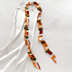 Robe en satin blanc accompagnée d'un foulard en soie aux motifs géométriques