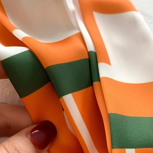 Gros plan d'un foulard en soie à imprimé géométrique, texture satinée et blocs de couleur
