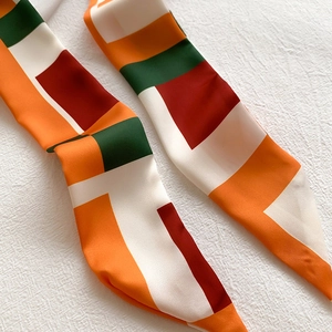 Détail d'un foulard en soie au motif géométrique color-block orange et vert