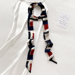 Détail d'un foulard en soie géométrique avec blocs rouges, bleus et blancs sur satin