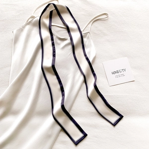 Robe nuisette blanche en soie et foulard noir contrasté à plat sur fond texturé élégant