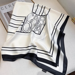 Foulard in seta blu e bianco con motivi geometrici su una sedia beige