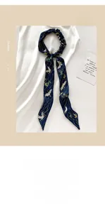 Detail eines schmalen blauen Seidenschals mit weißen Kranichen und Goldblättern