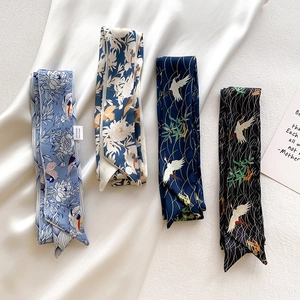 Detailaufnahme von Seidenschals mit Blumen- und Kranichmuster und Seidenpflegeetikett