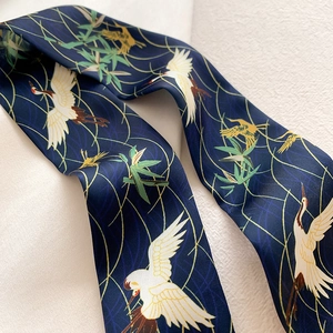 Nahaufnahme von Seidenschal mit elegantem Kranich- und Bambusmuster auf dunkelblauem Stoff