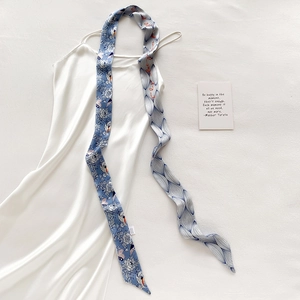 Detail eines blauen Seidenschals mit Blumen- und Vogelprint auf weißem Kleid