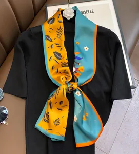 Detail of a double-layered silk twilly scarf with floral prints tied on a black sweater