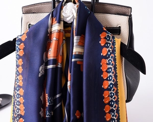 Detailed close-up of dark blue silk scarf featuring retro carriage and chain pattern