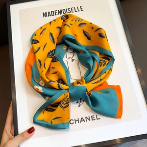 Detail of silk skinny scarf with yellow and teal floral patterns and rolled edge finish