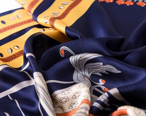 Macro detail of retro silk scarf showing smooth texture and chain patterns in navy and yellow