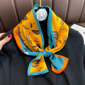 Close-up of silk scarf with floral leaf patterns and elegant orange satin borders