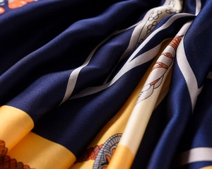 Close-up detail of silky carriage chain pattern scarf with deep blue and yellow satin texture