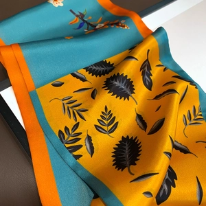 Detail showing the silk texture, vibrant floral prints, and fine rolled edges of the scarf