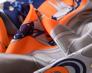 Macro detail of retro carriage pattern silk scarf showing fine texture and orange color