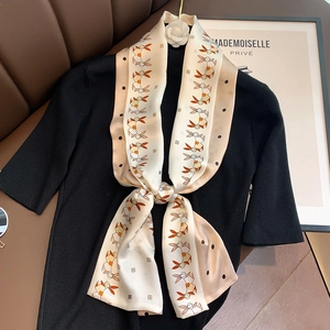 Detail of a patterned silk scarf with rabbit print and white camellia on a black sweater