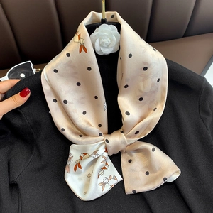 Detail of silk scarf with bunny and polka dot print tied on a black shirt collar