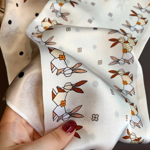 Detail of silk scarf texture featuring origami rabbit print and polka dot patterns