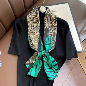 Detail of multi-color patterned silk scarf tied on a black knit sweater top