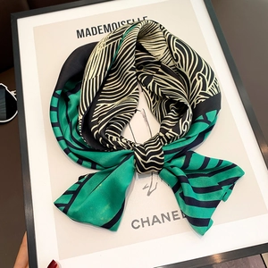 Detail of silk scarf tied in a bow featuring green and black geometric paisley patterns
