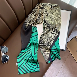 Detailed texture of a long silk scarf featuring geometric and wave patterns on a leather sofa