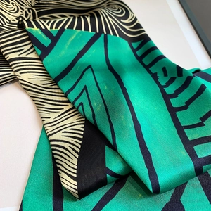 Detail of emerald and black geometric printed silk scarf with high gloss satin texture