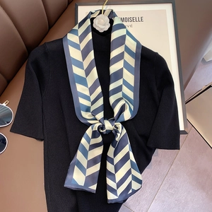 Close-up of silk scarf with blue and yellow chevron patterns styled on black knitwear