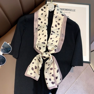 Detail of leopard print silk scarf tied on a black knit top with camellia hanger decor