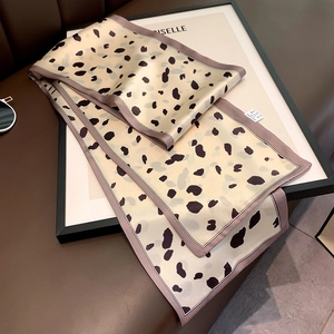 Close-up of printed silk neck scarf with leopard dots and woven laundry care label