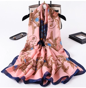 Detail of pink silk scarf with blue baroque floral patterns draped over a stylish handbag